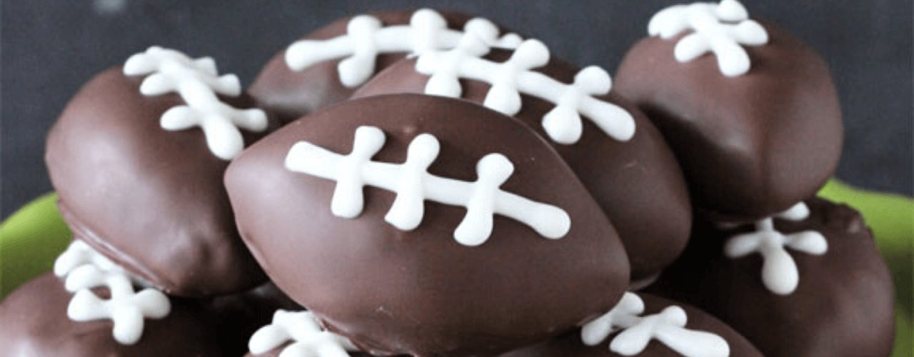 A plate full of chocolate covered treats in the shape of a football.