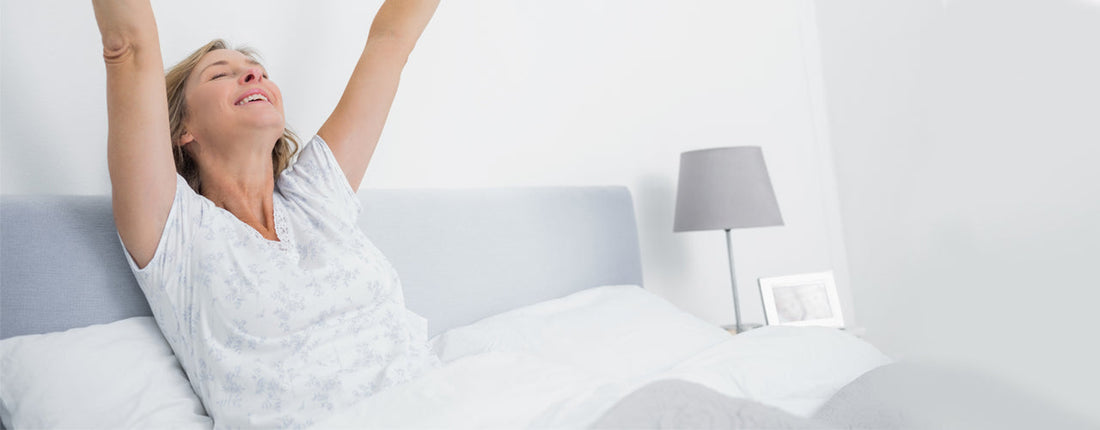 A woman waking up in the morning by stretching out her arms.