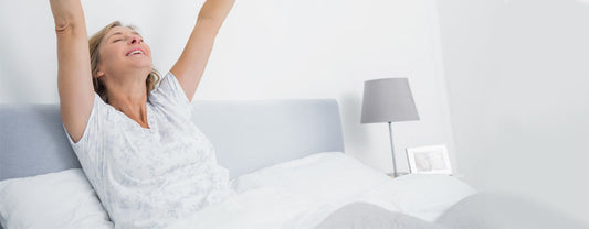 A woman waking up in the morning by stretching out her arms.