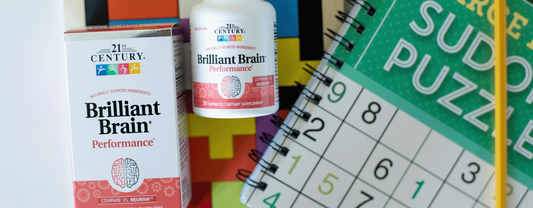 21st Century's Brilliant Brain product laying in the grass next to rubrics cubes.