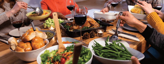 A group of people sitting at a dining room table enjoying Thanksgiving dinner.