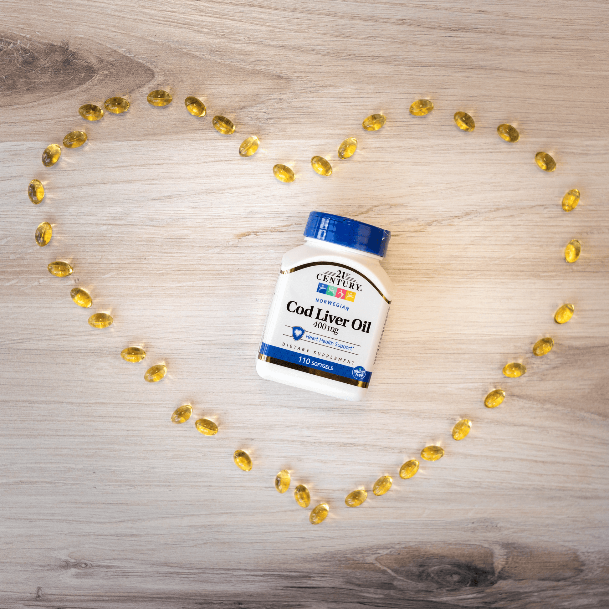 A bottle of 21st Century Norwegian Cod Liver Oil 400 mg softgels laying on a wood floor surrounded by softgels in the shape of a heart.