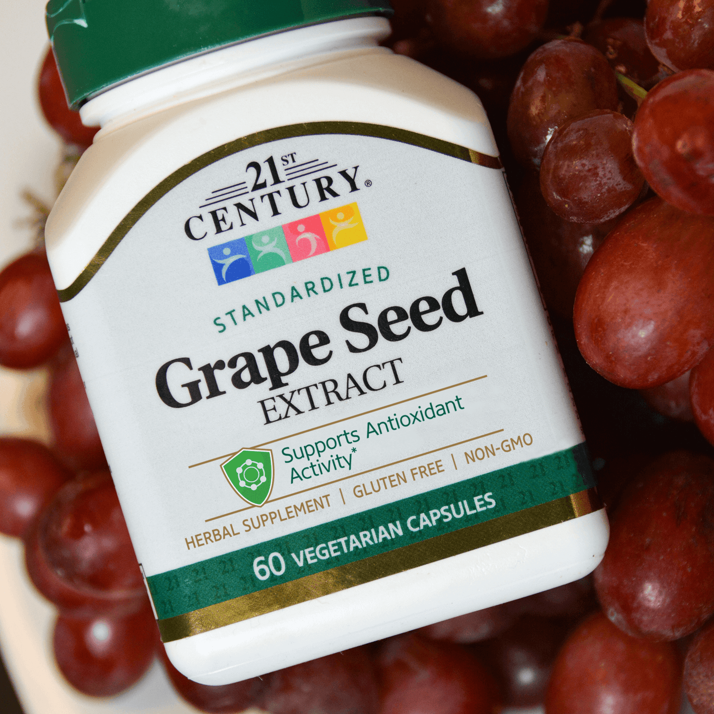 A bottle of 21st Century Grape Seed Extract vegetarian capsules laying on grapes.