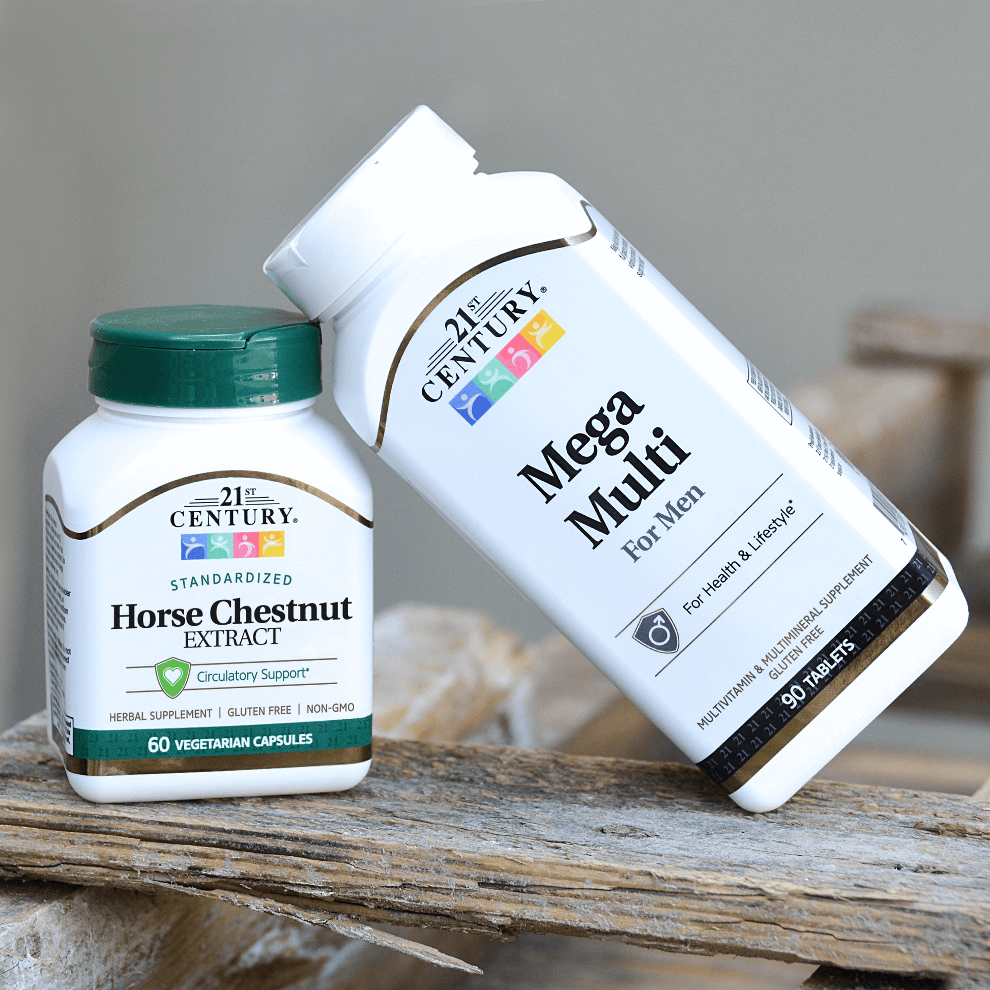 A bottle of Mega Multi Men's Multivitamin Multimineral tablet leaning on a bottle of 21st Century Horse Chestnut Extract vegetarian capsules on a piece of old wood.