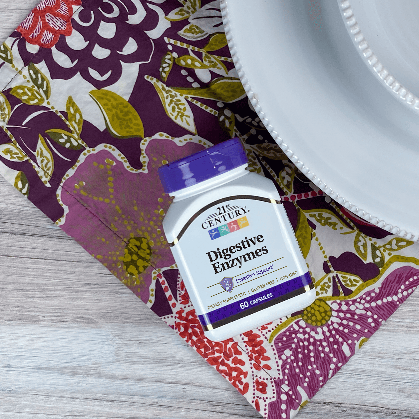 A bottle of 21st Century Digestive Enzymes capsules laying on a dinner plate mat next to a dinner plate.