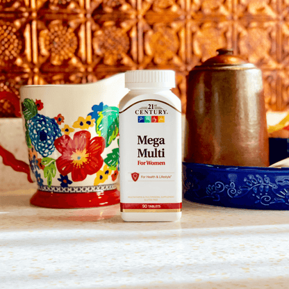 A bottle of 21st Century Mega Multi Women's Multivitamin and Multimineral tablets on a kitchen counter next to a beautiful tea cup and copper tea pot.