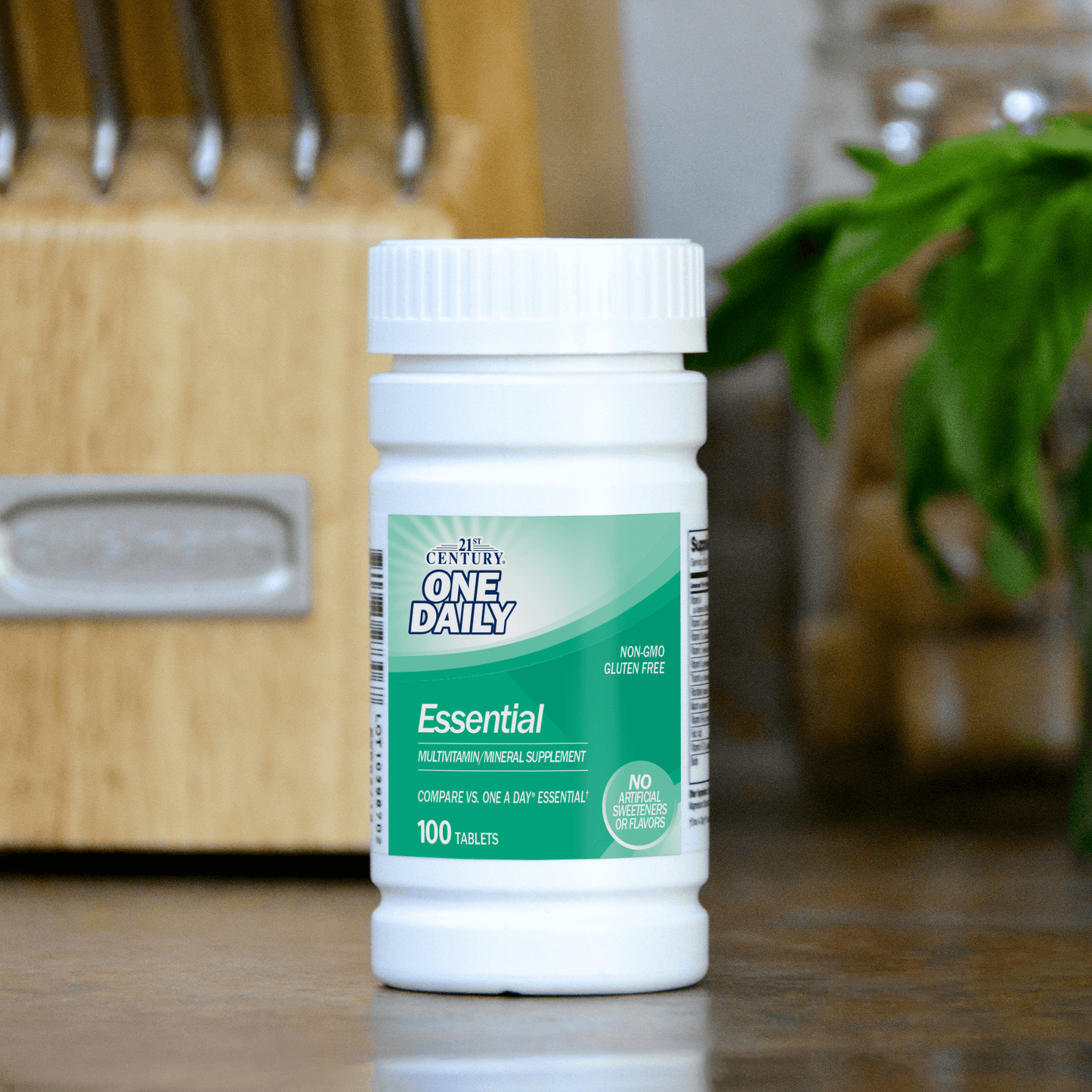 A bottle of 21st Century One Daily Essential multivitamin and mineral supplement tablets on a kitchen counter with a butcher block in the background.