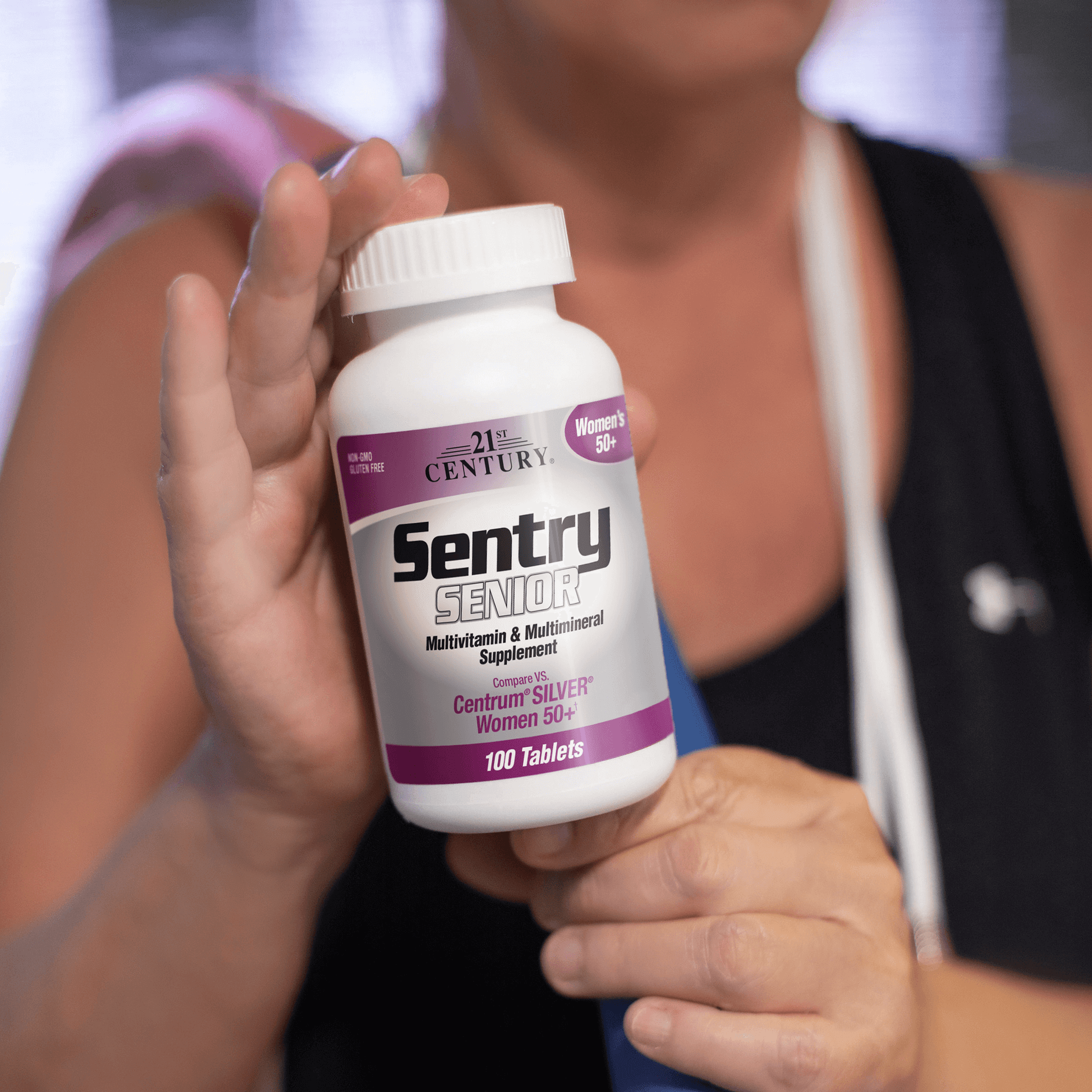 A senior woman holding a bottle of 21st Century Sentry Senior Women's 50+ Multivitamin and Multimineral tablets.