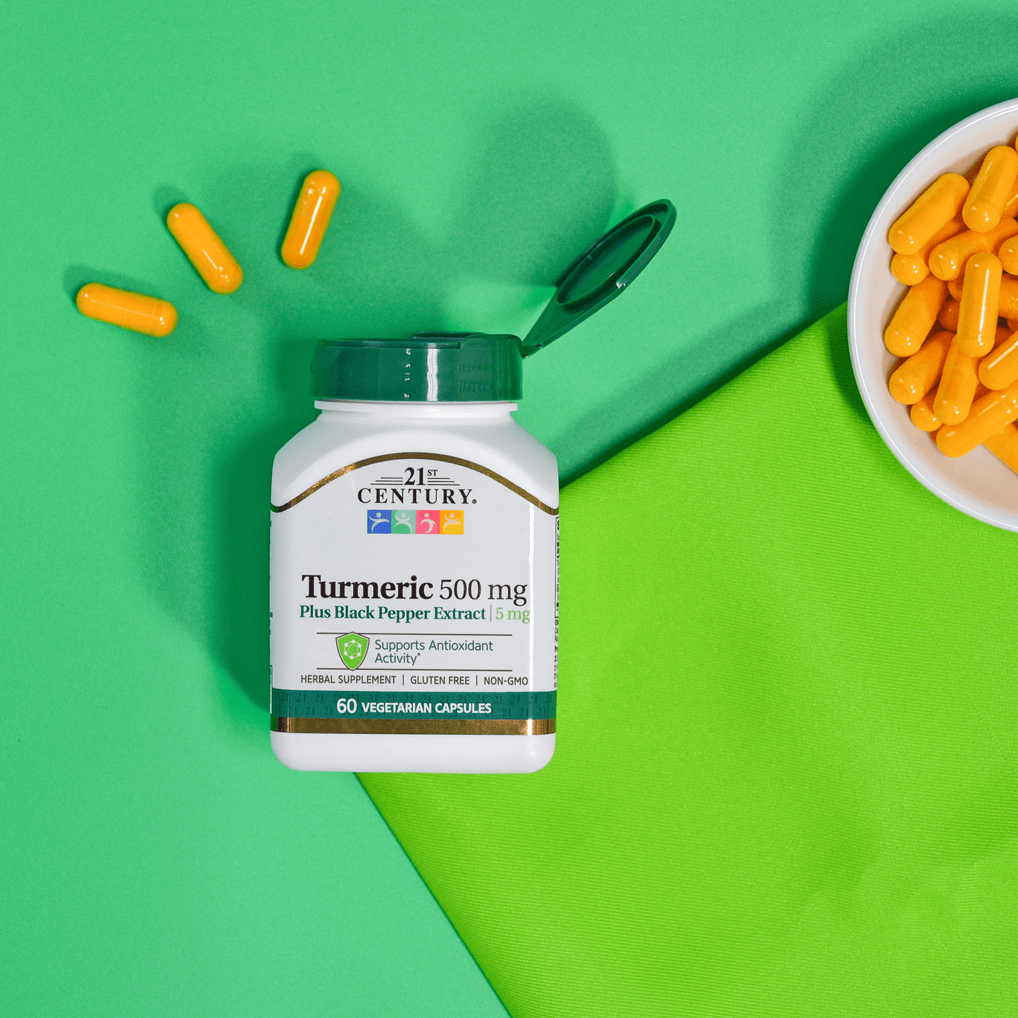 A bottle of 21st Century Turmeric 500 mg Plus Black Pepper Extract vegetarian capsules laying on a background with a bowl of turmeric capsules.