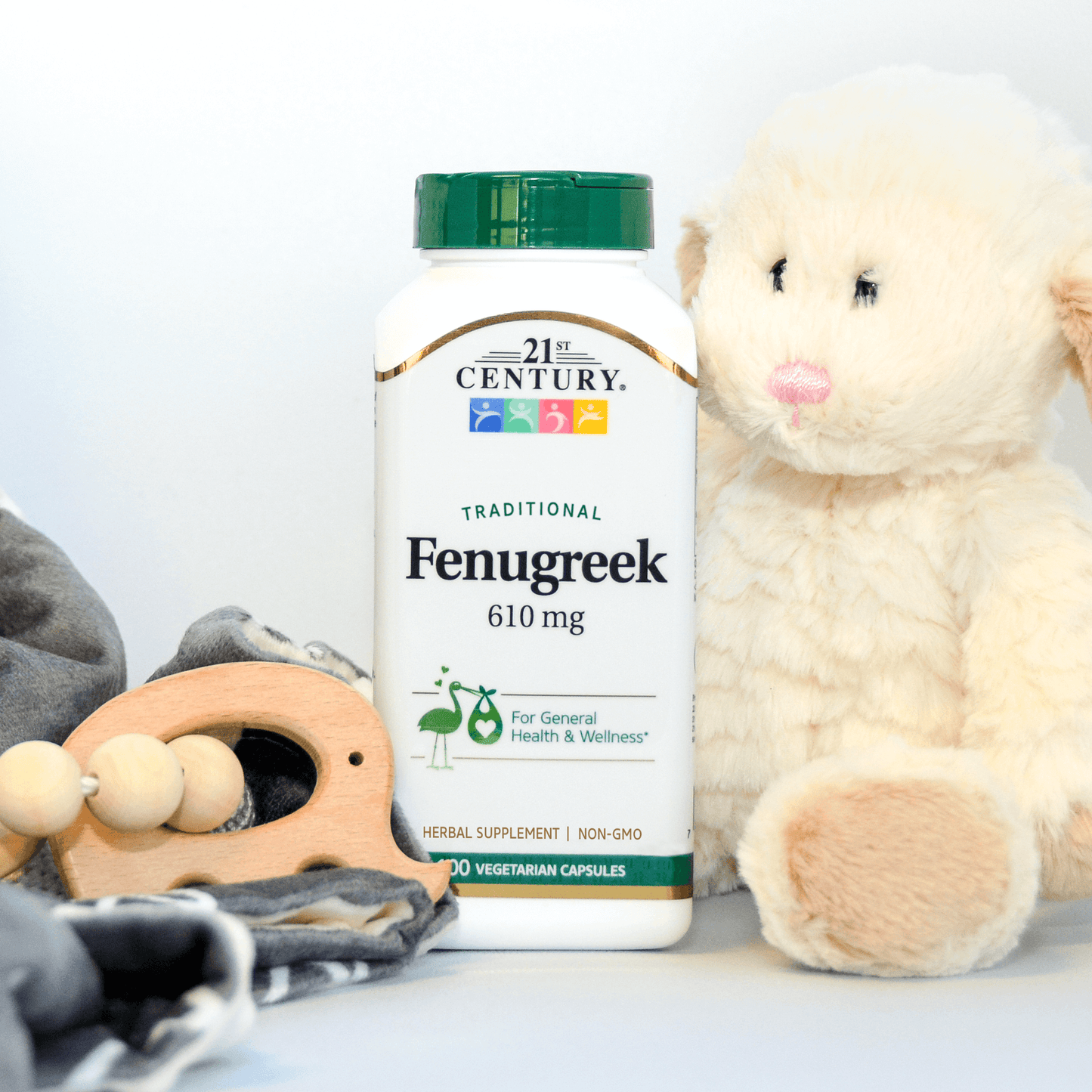 A bottle of 21st Century Fenugreek 610 mg vegetarian capsules next to a stuffed animal lamb and wooden teething toy.