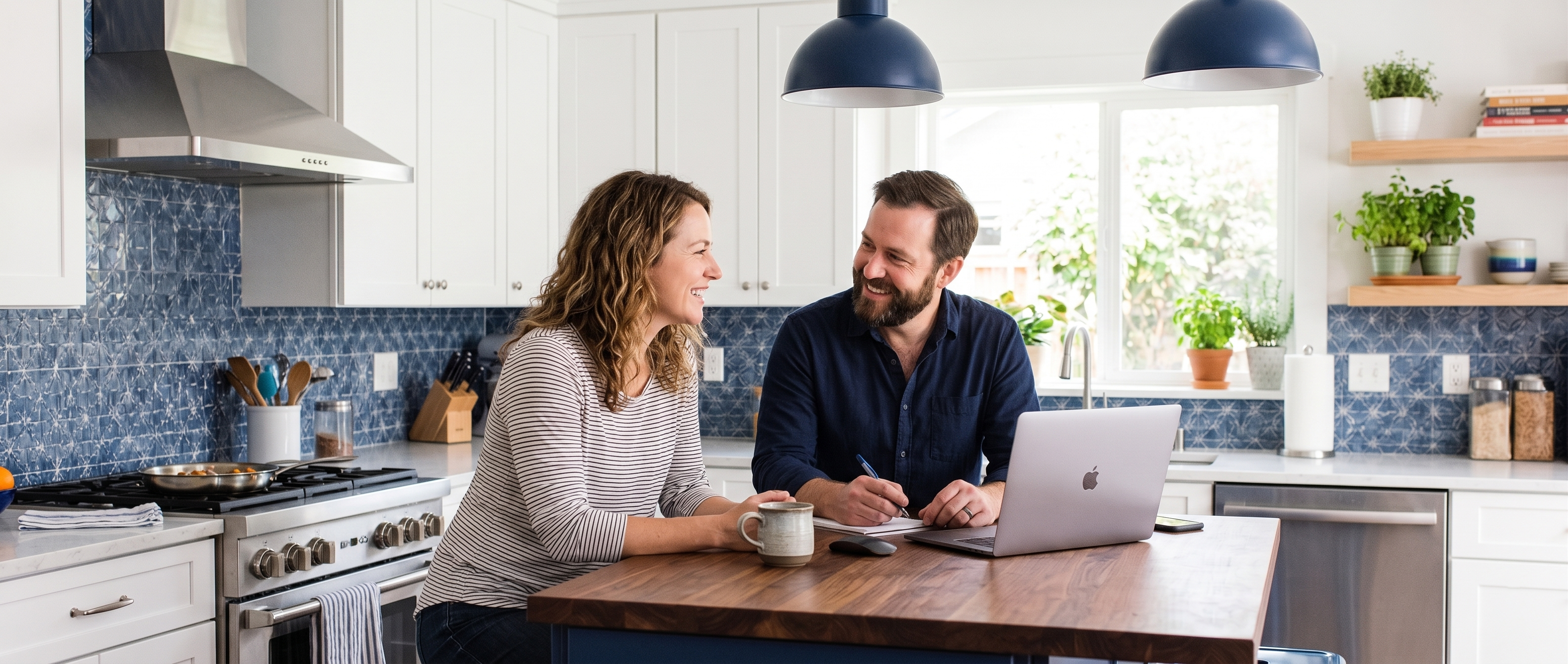 Man and woman smiling at a kitchen island with a laptop open