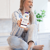 A women sitting crossed legged on a kitchen counter laughing with bottle of 21st Century Acidophilus Probiotic Blend capsules.