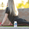 A bottle of 21st Century Calcium Citrate Maximum plus D3 tablets in front of a blonde girl stretching on a yoga mat.