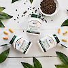 A bottle of 21st Century Turmeric Curcumin 95, Turmeric Complex 500 mg and Turmeric 500 mg Plus Black Pepper Extract laying on a wood background with whole black pepper in a bowl, leaves and turmeric capsules.