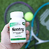 Holding a bottle of 21st Century Sentry Adults Multivitamin and Multimineral tablets with two tennis rackets and a tennis ball on the round in the background.