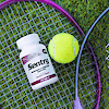A bottle of 21st Century Sentry Women's Multivitamin and Multimineral tablets laying on a tennis racket next to a tennis ball.