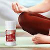 A bottle of 21st Century One Daily Maximum Multivitamin and Multimineral tablets next to a woman meditating.