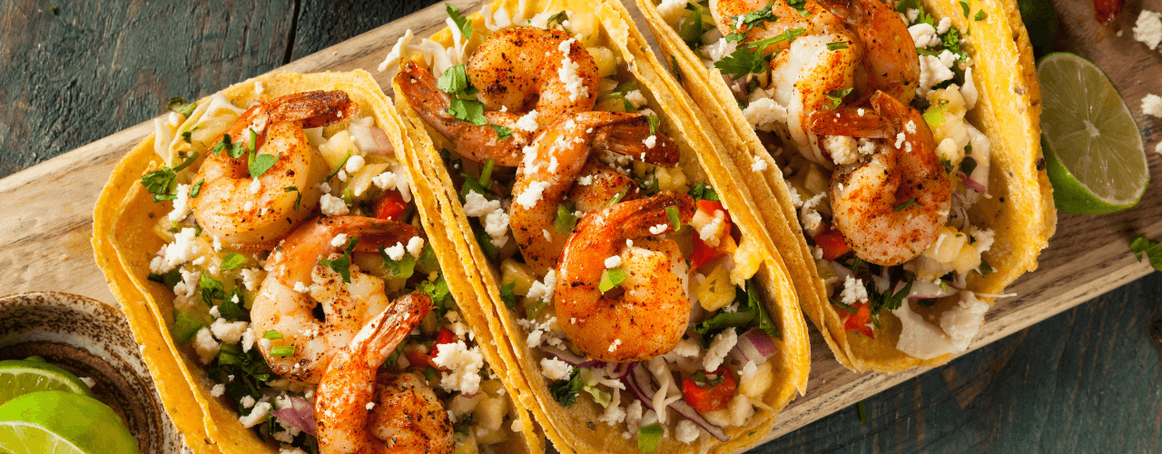 Delicious looking shrimp tacos on wood plank table top.