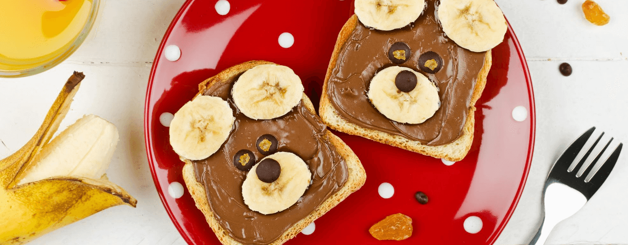 Peanut butter toast with bananas on top in the shape of a bear's face.