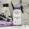 A bottle of 21st Century Daily Amino Acid tablets with gym shoes, a backpack and a water bottle in the background.