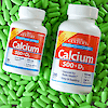 Two bottles of 21st Century Calcium 500 plus D3 tablets laying on top of tablets.