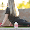 A bottle of 21st Century Calcium 500 plus D3 tablets with a blonde woman in the back on a yoga mat stretching.