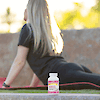 A bottle of 21st Century Calcium 600 plus D3 tablets with a blonde woman in the back on a yoga mat in the back stretching.