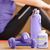 A bottle of 21st Century Calcium 600 plus D3 plus minerals chewable tablets next to dumbbells and a water bottle with a woman sitting in the background.