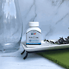 A bottle of 21st Century Iron 27 mg Ferrous Gluconate high potency tablets sitting on a tray next to a glass vase.