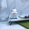 A bottle of 21st Century Iron 65 mg 325 mg Ferrous Sulfate high potency tablets on a tray next to a glass vase.