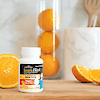 A bottle of 21st Century ImmuBlast chewable tablets on a counter with oranges and wooden kitchen utensils.